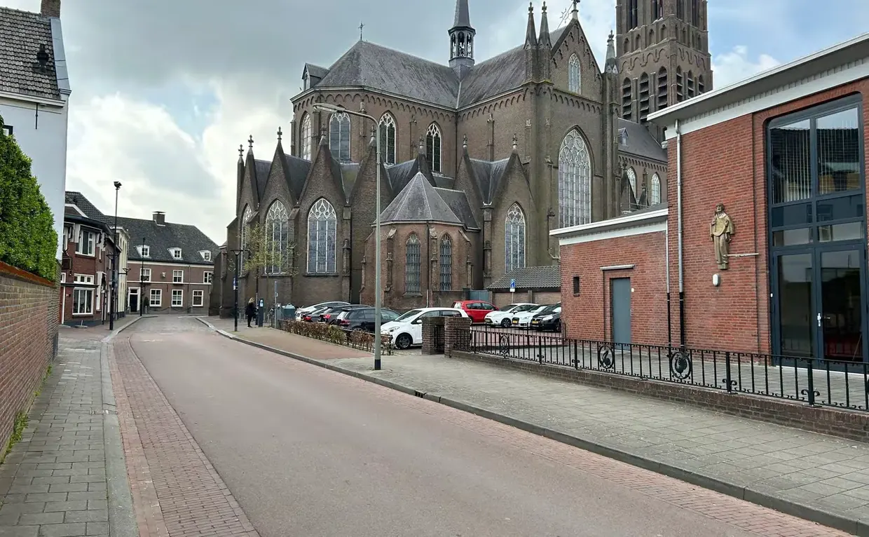 De Koornstraat voor de verbouwing: geparkeerde auto's langs het hek, met de kerk erachter.
