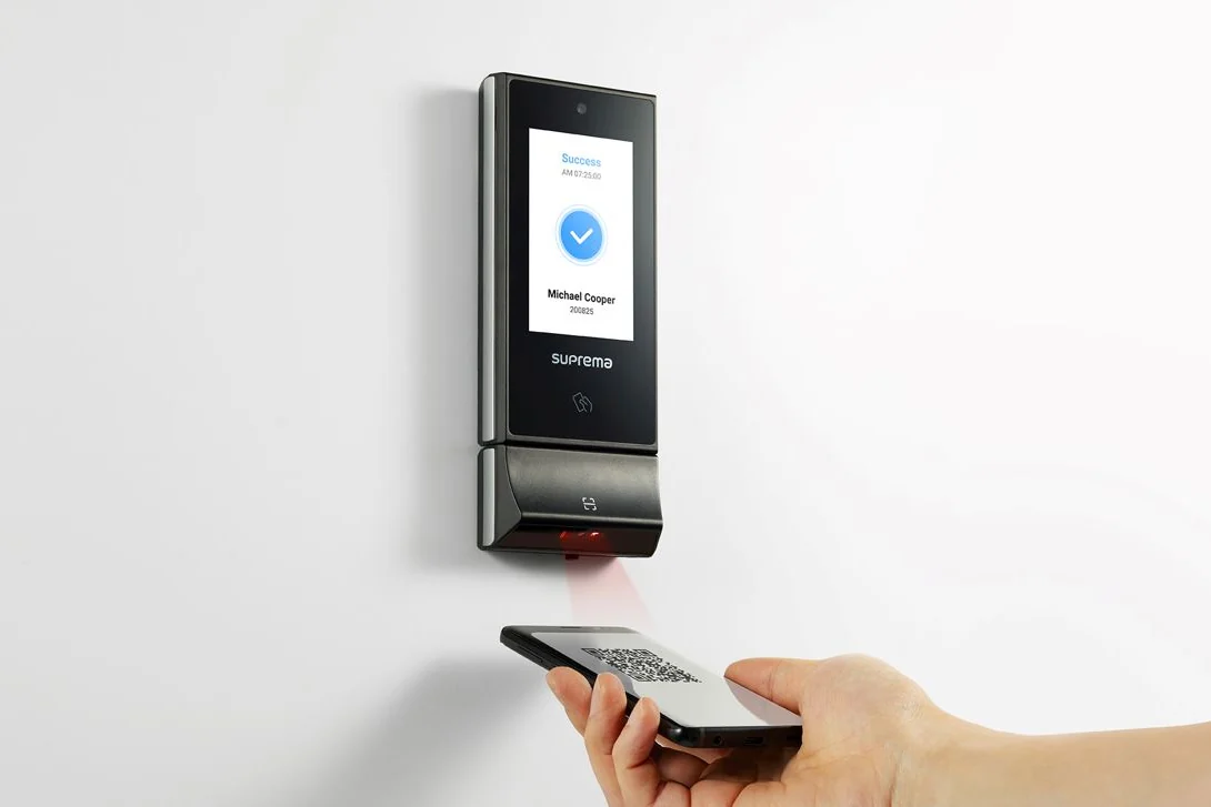 Iemand houdt een telefoon met een QR-code voor een lezer naast een deur.